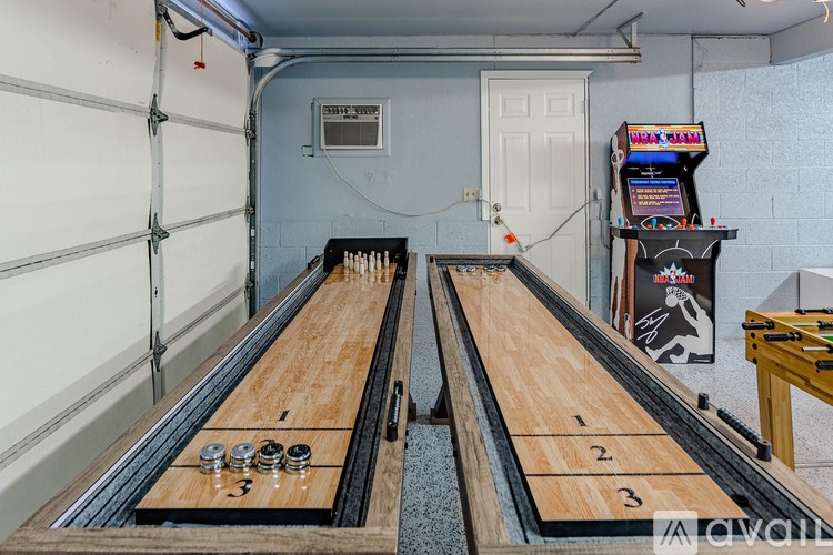 A room with two lanes of bowling pins and a shelf with arcade games.