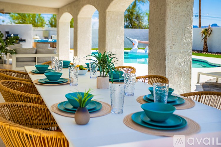 A table set for a meal with a view of a pool and palm trees.