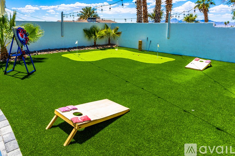 A backyard with a putting green and a wooden table.