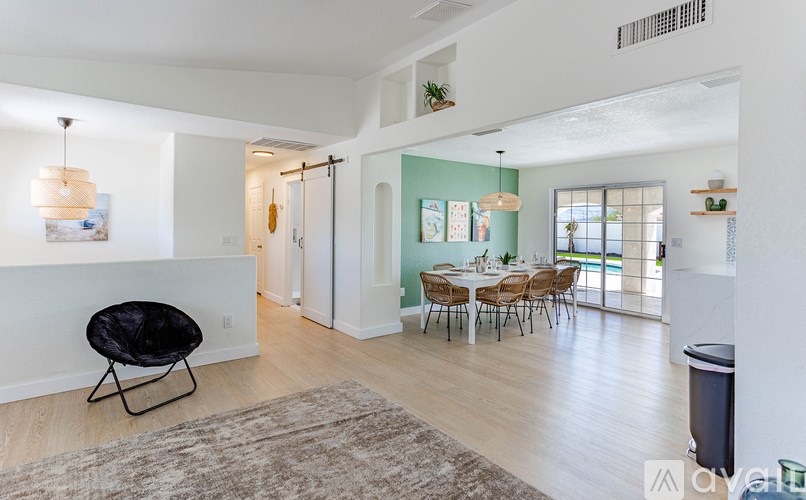 A living room with a black chair and a dining table with chairs.