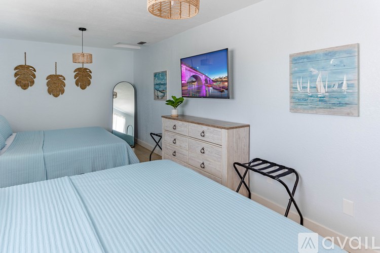A bedroom with two beds, a dresser, and a television.