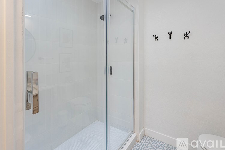 A bathroom with a glass shower door and three stick figures on the wall.