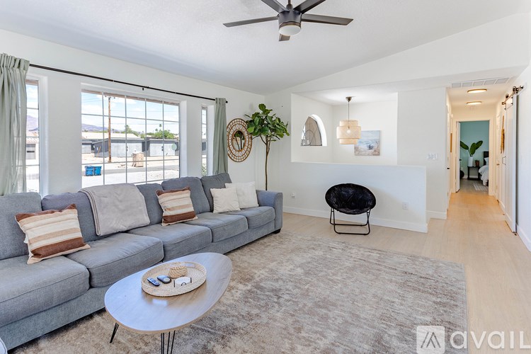 A living room with a grey sofa, a round table, and a ceiling fan.