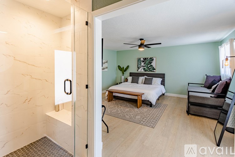 A bedroom with a bed, chair, and a plant.