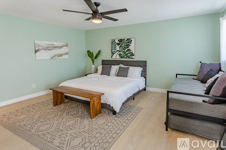 A bedroom with a bed, a bench, and a ceiling fan.