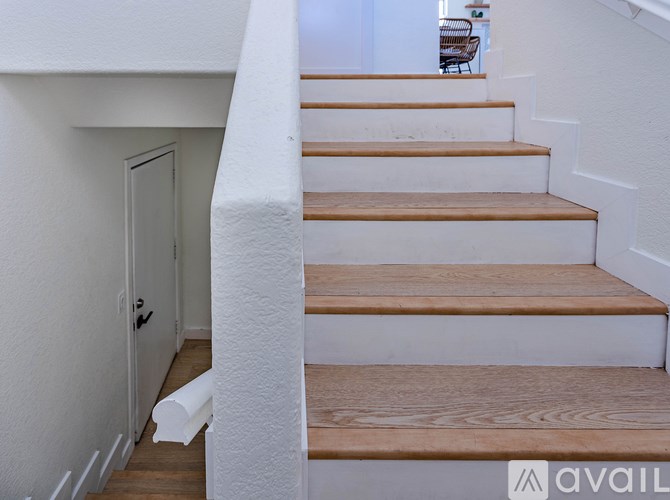 A set of wooden stairs with white walls on either side.
