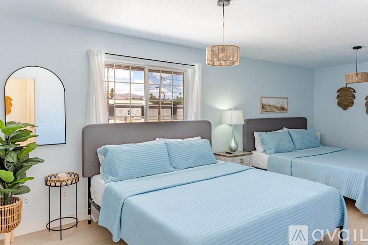 A bedroom with two beds, one with a blue bedspread and a mirror on the wall.