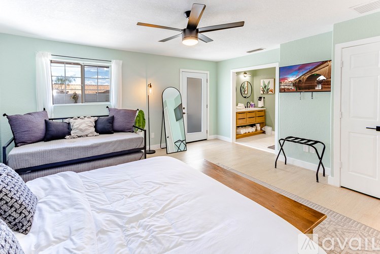 A bedroom with a bed, a couch, a mirror, and a ceiling fan.
