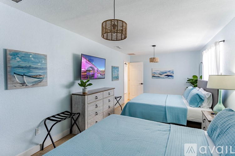 A bedroom with two beds, a TV, and a painting on the wall.