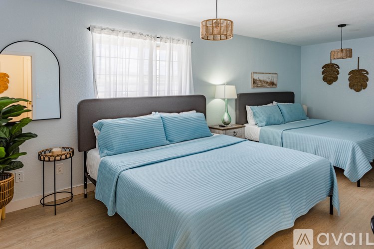 Two beds with blue bedspreads in a room.