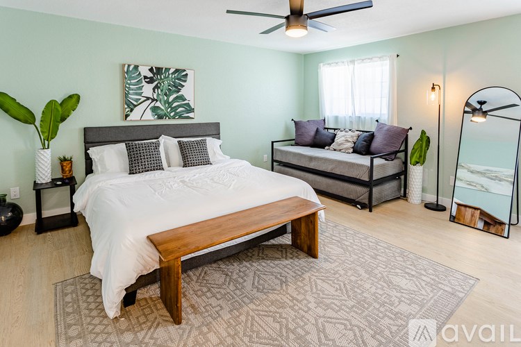 A bedroom with a large bed and a bench in the middle.