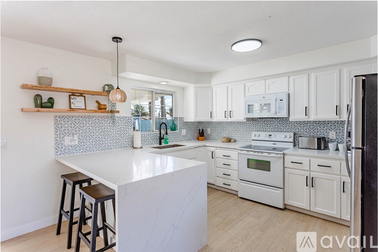 A kitchen with white cabinets and a white island with bar stools.