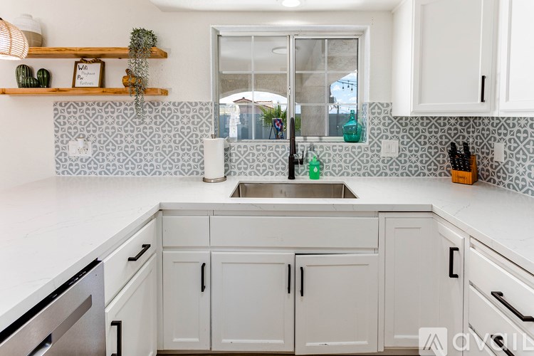A kitchen with white cabinets and a patterned backsplash.