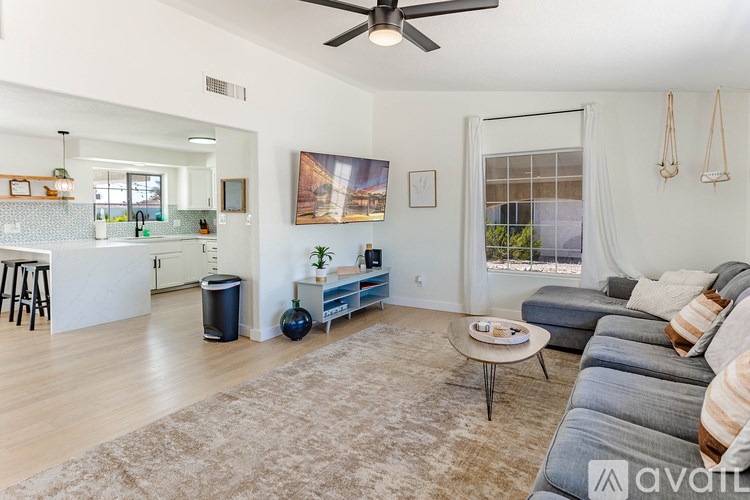 A living room with a grey couch and a white ceiling fan.