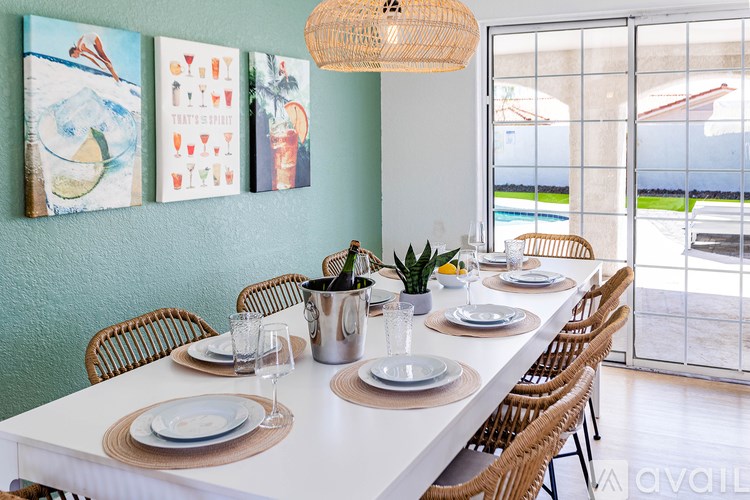 A dining table set for a meal with a view of the pool outside.
