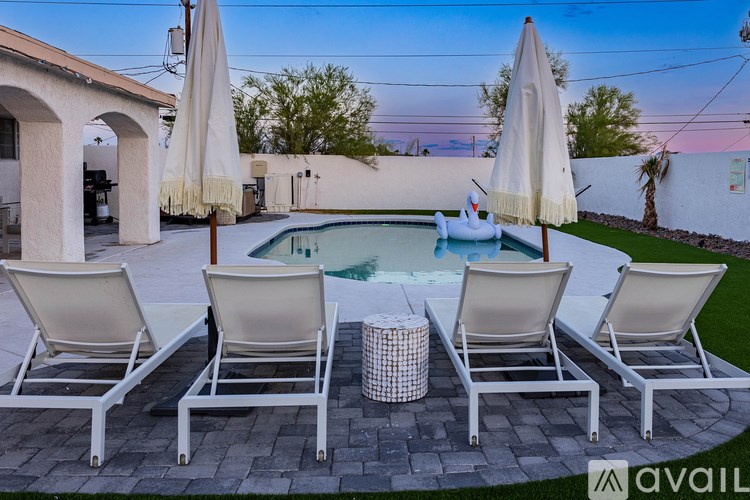 A poolside seating area with white chairs and umbrellas.
