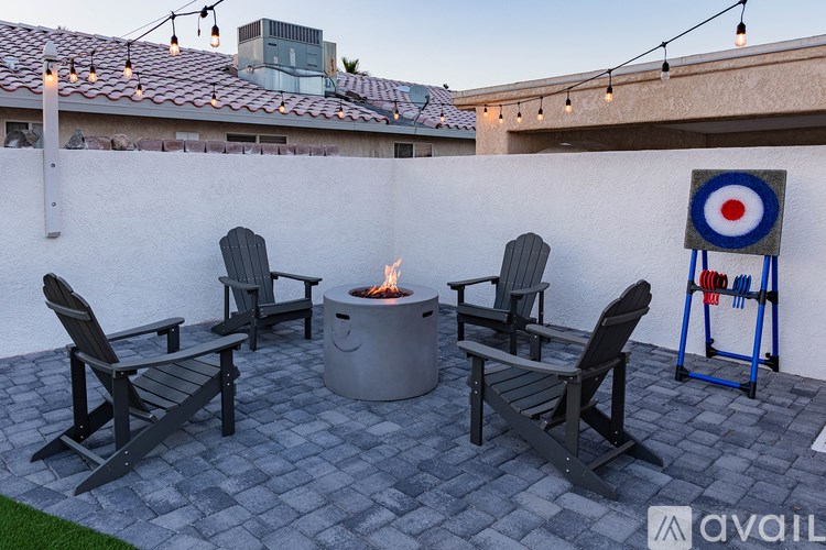 A patio with a fire pit and chairs.