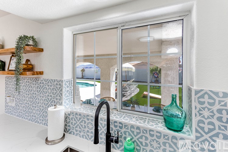 A bathroom with a blue and white tiled wall and a glass shower door.
