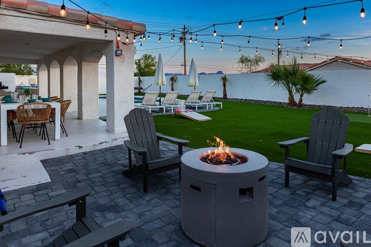 A patio with a fire pit and chairs.
