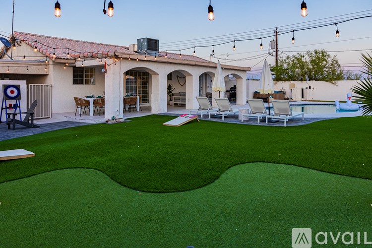 A backyard with a putting green and patio furniture.