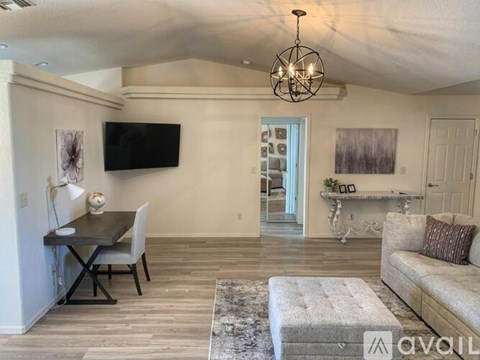 A living room with a couch, a chair, a coffee table, and a television mounted on the wall.