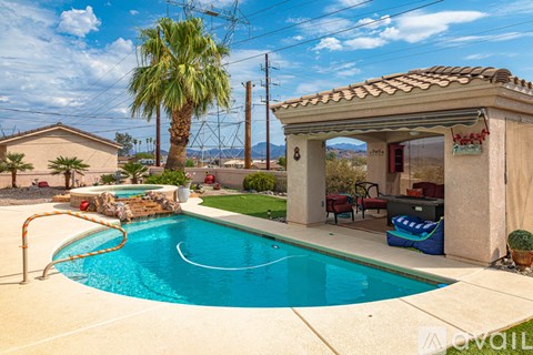 A pool with a slide and a house with a patio.