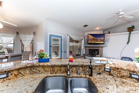 A kitchen with a stone counter top and a sink.