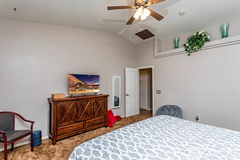 A bedroom with a bed, chair, and painting on the wall.