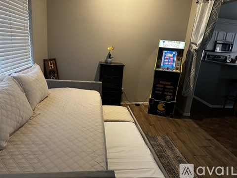 A living room with a couch, a small table with a flower vase, and a cabinet with a video game console.