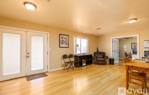 A living room with a wooden floor and a dining table with chairs.