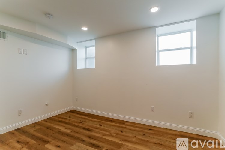 A room with wooden floors and two windows.