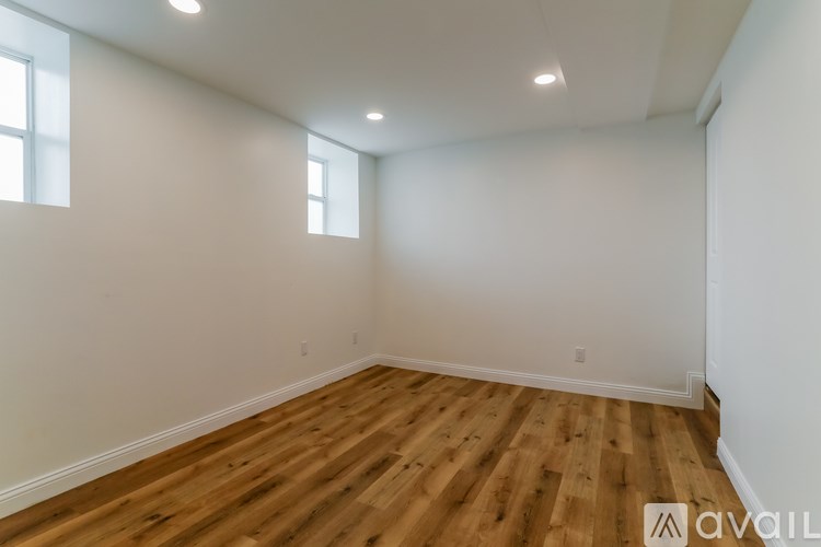 A room with wooden flooring and two windows.