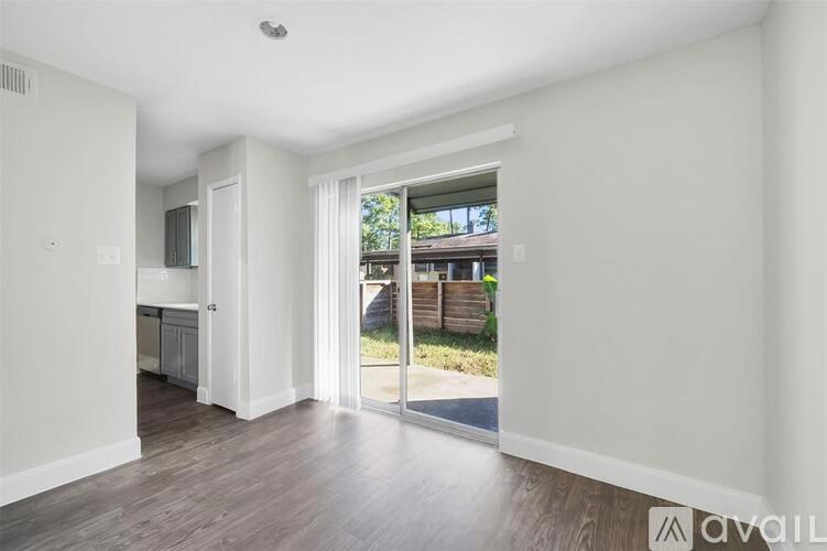 A spacious room with a view of a wooden fence and greenery outside.