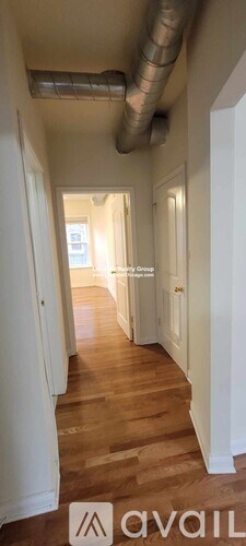 A hallway with wooden floors and white walls.