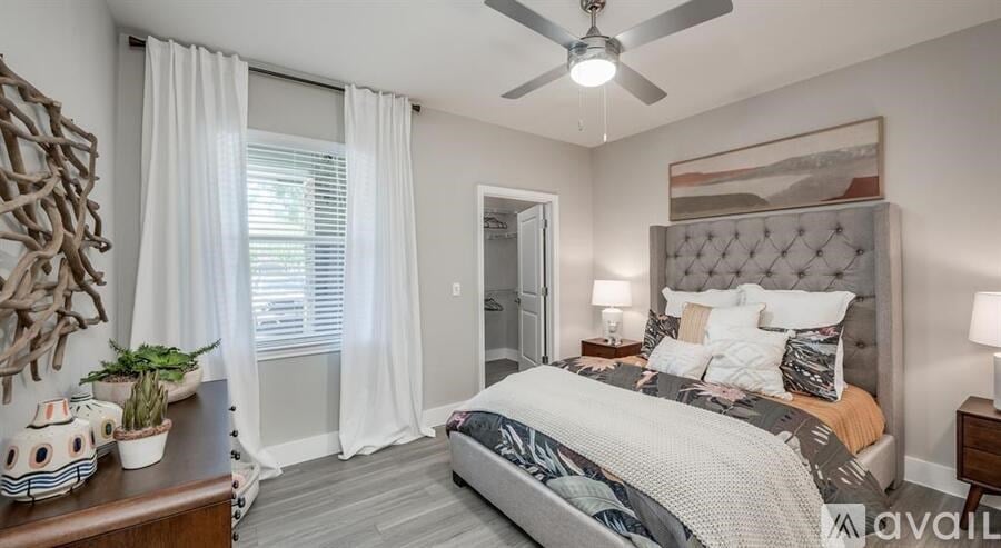 A bedroom with a large bed, a ceiling fan, and a wooden table with a plant on it.