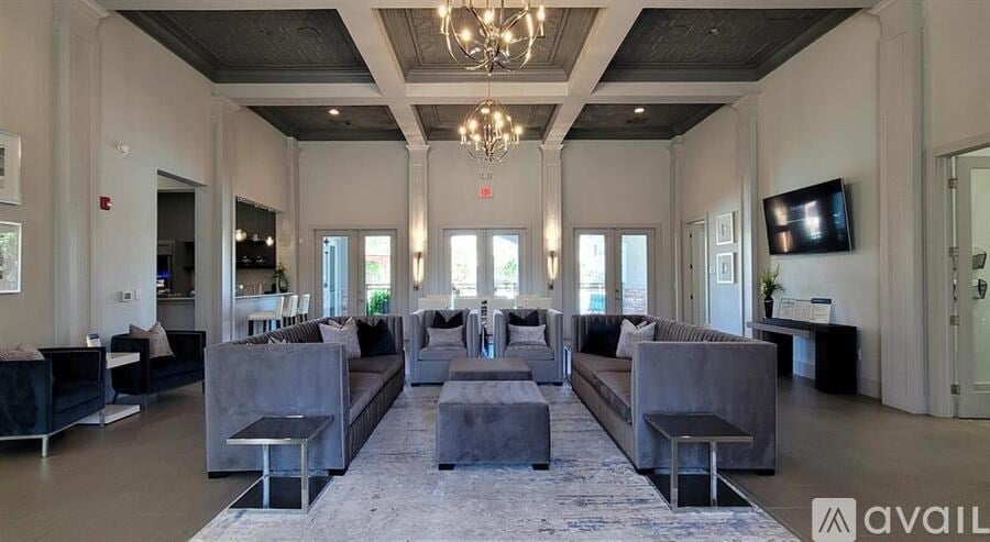 A spacious living room with grey furniture and a chandelier.