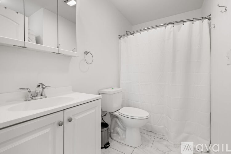 A white bathroom with a toilet, sink, and shower.