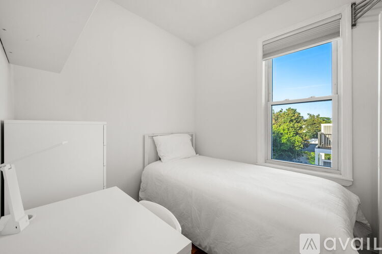 A bedroom with a large bed and a window overlooking a green landscape.
