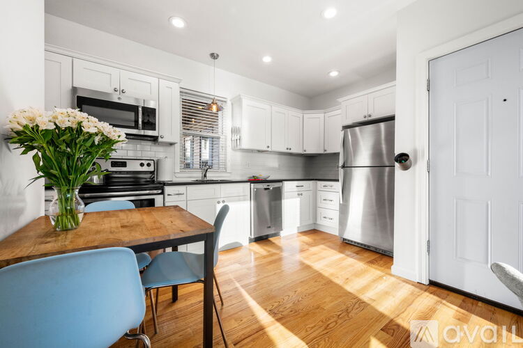 A kitchen with a table and chairs and a vase of flowers.