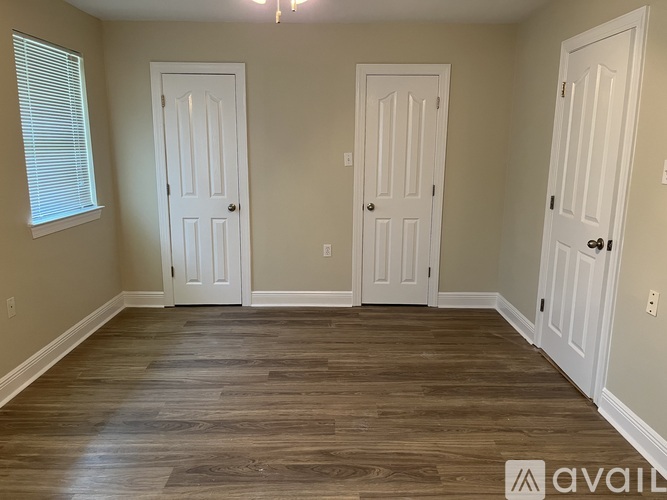 Three white doors are in a room with wood floors.