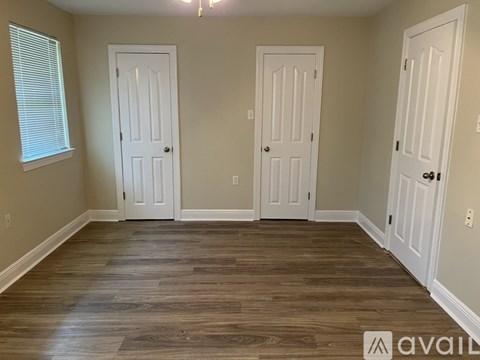 Three white doors are in a room with wood floors.
