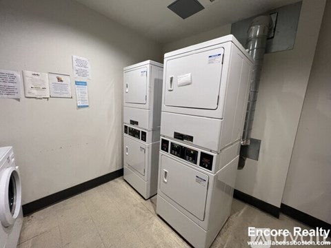 A wall of washers and dryers in a laundromat.