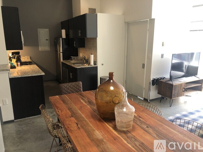 A kitchen with black cabinets and a wooden table with a vase on it.