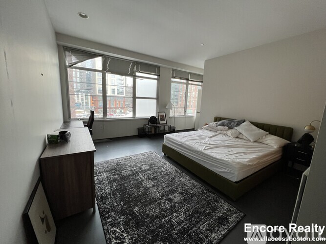 A bedroom with a large bed and a window overlooking a city street.
