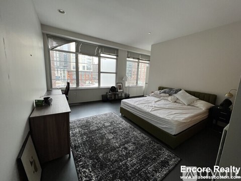 A bedroom with a large bed and a window overlooking a city street.
