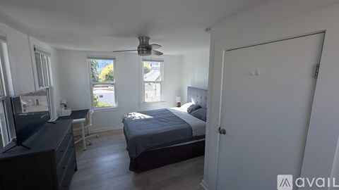 A bedroom with a bed, desk, and window.