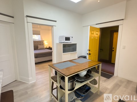 A kitchen area with a table and a microwave on top of a cabinet.