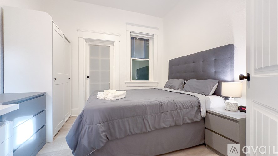 A bedroom with a bed, nightstand, and window.