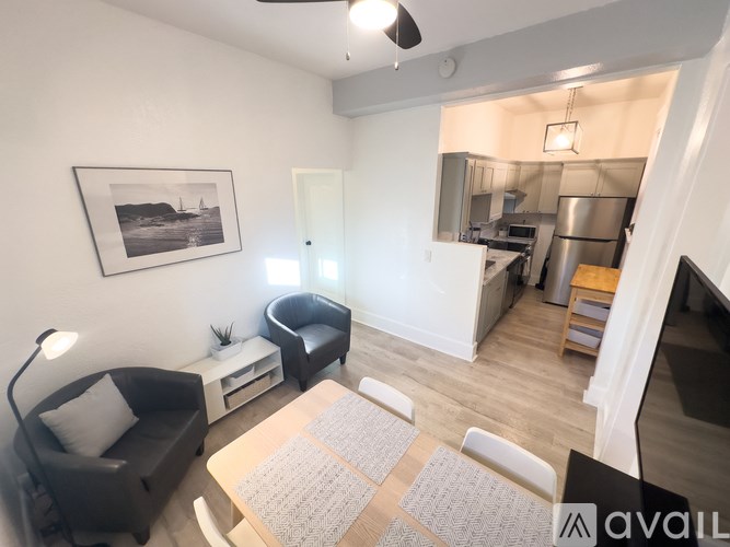 A living room with a black couch, a grey rug, and a framed picture on the wall.