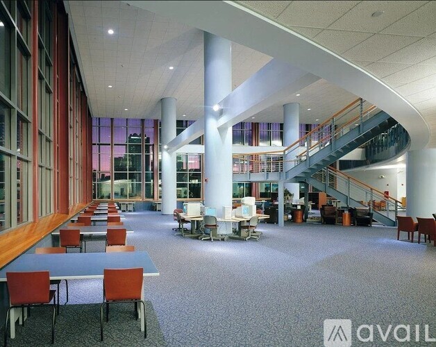 A spacious room with tables and chairs and a staircase.
